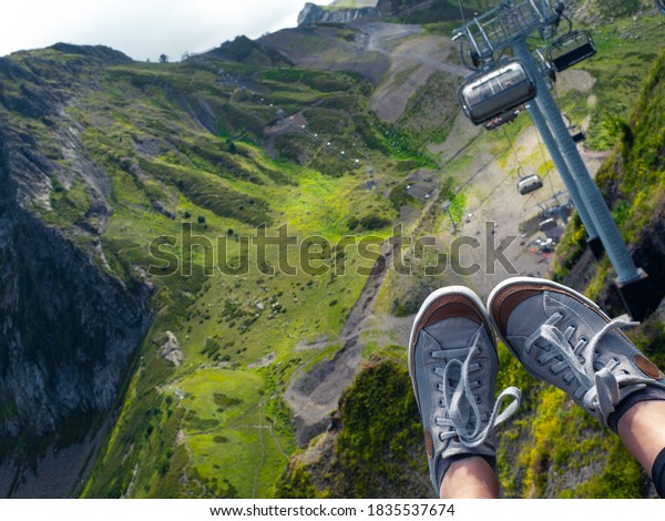 Beautiful cable\
car ride, sneakers on the background of a mountain landscape,\
first-person photo. beautiful landscape, Infrastructure for\
traveling in the mountains. Chair\
lift.