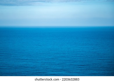 Beautiful Calm And Peaceful Water Flowing With Waves Towards Beach With Green Tall Trees Against Cloudy Blue Sky During Daytime With No People Around