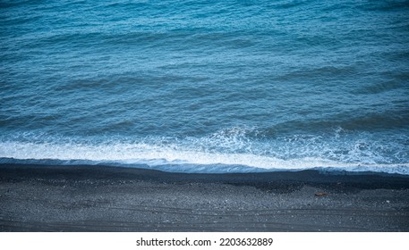 Beautiful Calm And Peaceful Water Flowing With Waves Towards Beach With Green Tall Trees Against Cloudy Blue Sky During Daytime With No People Around