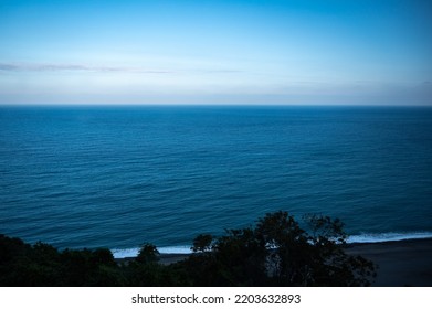 Beautiful Calm And Peaceful Water Flowing With Waves Towards Beach With Green Tall Trees Against Cloudy Blue Sky During Daytime With No People Around