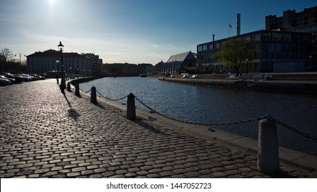 Beautiful calm summer afternoon at Rosenlund canal in Gothenburg city centre Sweden, with the historic Fiskekyrkan fish market building, wrought iron street light lampposts, stone bollards and chains