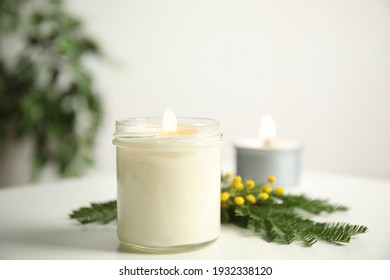 Beautiful Candle With Wooden Wick And Flowers On White Table