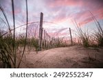 A beautiful cape cod sunset with a rugged fence to emphasize the clouds and sunset