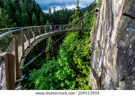 Beautiful Capilano Cliff Walk Suspension Bridge with Tourists Enjoying the View, in Vancouver.