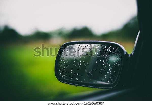 Beautiful car mirror with water droplets and\
colorful bokeh