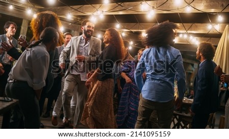 Beautiful Carefree Friends are Dancing Together and Celebrating an Evening Event at a Party . Diverse Multiethnic Young Adult People Have Fun at a Corporate Party in a Restaurant.