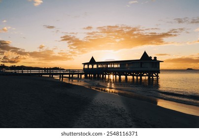 A beautiful Caribbean sunset with a wooden pier stretching over calm waters. The warm golden hues and reflections on the ocean create a serene and idyllic coastal scene in the fading light. - Powered by Shutterstock