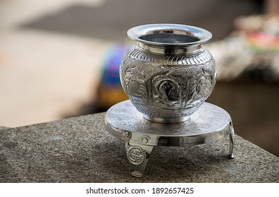 Beautiful carved silver pot or kalash and stand used in hindu rituals, on blur background.