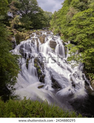 Beautiful cascading waterfall through a lush green landscape - Rhaeadr Ewynnol  Swallow Falls in Betws y Coed, North Wales