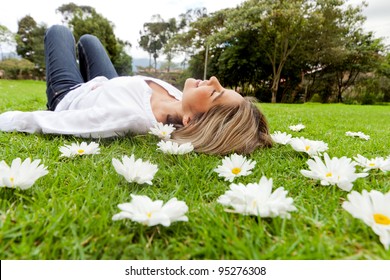Beautiful casual woman relaxing outdoors lying on the grass