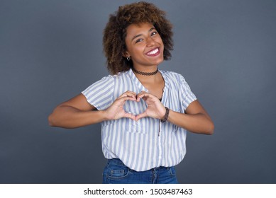 Beautiful caucasian African American woman over isolated background smiling in love showing heart symbol and shape with hands. Romantic concept.