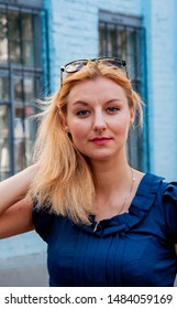 Beautiful Caucasian Blonde Girl Posing Outdoors. Young Woman Looking into Camera. Sexual Lady is Serious. Daytime. Closeup. Woman Touching Her Hair. Girl Standing on Street in Kyiv, Ukraine.