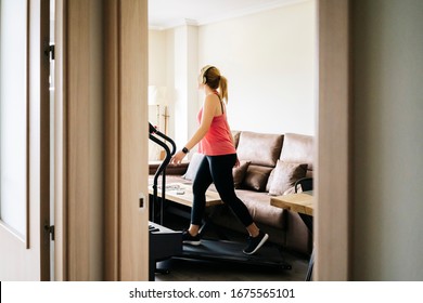 Beautiful caucasian blonde woman exercises on a treadmill in her living room - Powered by Shutterstock