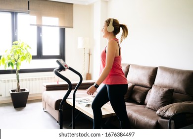 Beautiful Caucasian Blonde Woman Exercises On A Treadmill In Her Living Room. Workout.