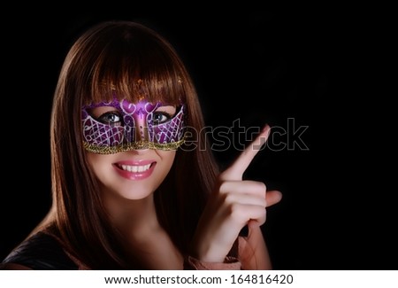 Beautiful caucasian brunette in carnival mask over black background