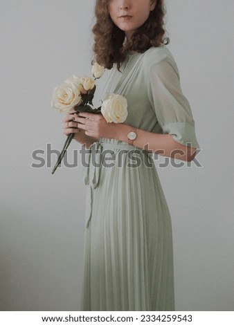 A beautiful Caucasian brunette in Victorian style chiffon dress holding beige roses