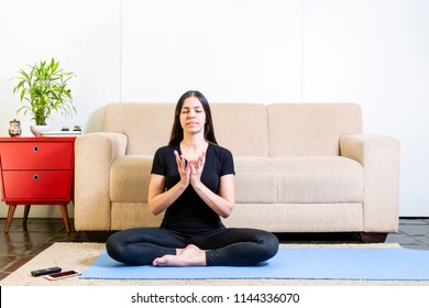 Beautiful Caucasian Brunette Woman In Black Clothes On Blue Yogamat Doing Lotus Mudra