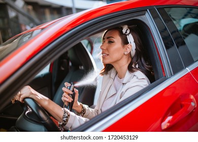 Beautiful caucasian businesswoman puts perfume in car