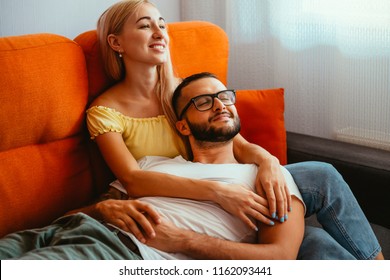 Beautiful Caucasian Couple Bonding On An Orange Couch At Home, Watching TV Series Together. Grain Effect.