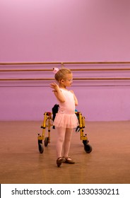 Beautiful Caucasian Female Child Tap Dancer Wearing Pink Ballet Leotard Dances Beside Her Gold Walker Mobility Aid While Wearing Glasses And Hearing Aids 