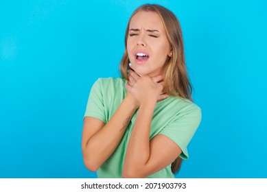 Beautiful caucasian girl wearing green T-shirt over isolated background shouting suffocate because painful strangle. Health problem. Asphyxiate and suicide concept.