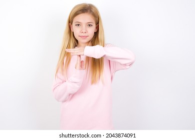 beautiful caucasian little girl wearing pink sweater over white background feels tired and bored, making a timeout gesture, needs to stop because of work stress, time concept.