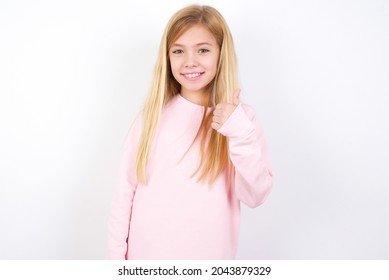 Beautiful Caucasian Little Girl Wearing Pink Sweater Over White Background Giving Thumb Up Gesture, Good Job! Positive Human Emotion Facial Expression Body Language.