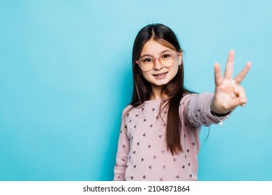 beautiful caucasian little girl wearing striped dress over blue background showing and pointing up with fingers number three while smiling confident and happy.