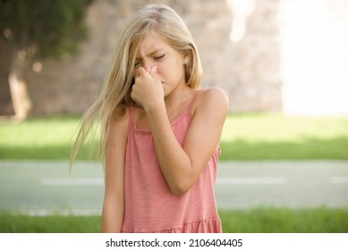 Beautiful Caucasian Little Kid Girl Wearing Dress Standing Outdoors , Holding His Nose Because Of A Bad Smell.