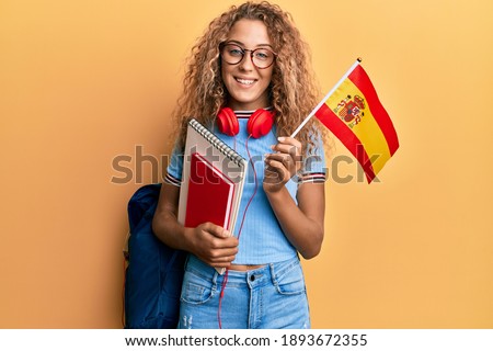 Beautiful caucasian teenager girl exchange student holding spanish flag smiling with a happy and cool smile on face. showing teeth. 