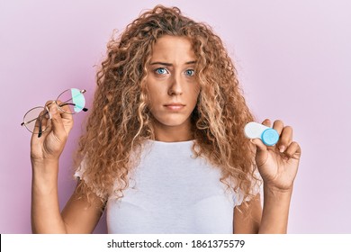 Beautiful caucasian teenager girl holding glasses and contact lenses skeptic and nervous, frowning upset because of problem. negative person. 