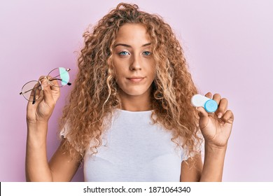 Beautiful caucasian teenager girl holding glasses and contact lenses relaxed with serious expression on face. simple and natural looking at the camera. 