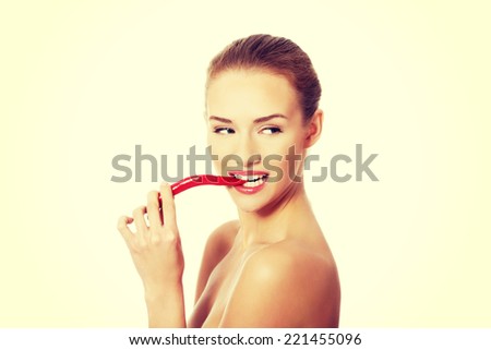 Beautiful caucasian topless woman with chili pepper in mouth. Isolated on white.