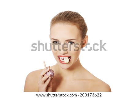 Beautiful caucasian topless woman with raw garlic in mouth. Isolated on white.