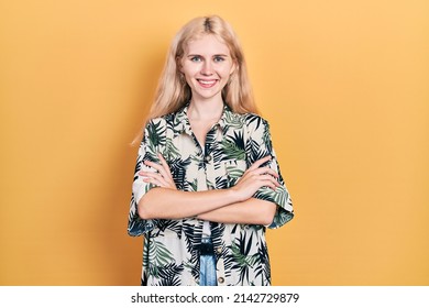 Beautiful caucasian woman with blond hair wearing tropical shirt happy face smiling with crossed arms looking at the camera. positive person. 