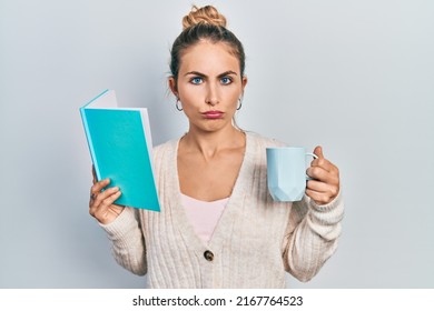 Beautiful caucasian woman with blond hair reading a book and drinking a cup of coffee depressed and worry for distress, crying angry and afraid. sad expression. 