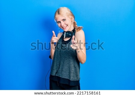Beautiful caucasian woman with blond hair wearing sportswear pointing fingers to camera with happy and funny face. good energy and vibes. 