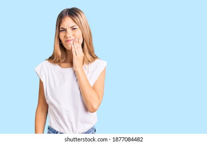 Beautiful caucasian woman with blonde hair wearing casual white tshirt touching mouth with hand with painful expression because of toothache or dental illness on teeth. dentist 
