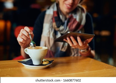 Beautiful Caucasian woman with coffee looking at her tablet	