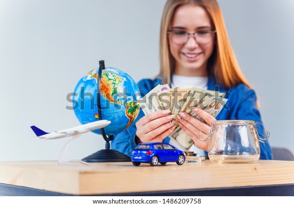 Beautiful\
caucasian woman in denim shirt counts money for future trip around\
world and feels happiness. Travel\
concept.