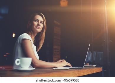 Beautiful Caucasian woman dreaming about something while sitting with portable net-book in modern cafe bar, young charming female freelancer thinking about new ideas during work on laptop computer  