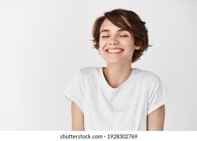 Beautiful caucasian woman dreamy smiling with eyes closed, standing relaxed and happy against white background. Copy space