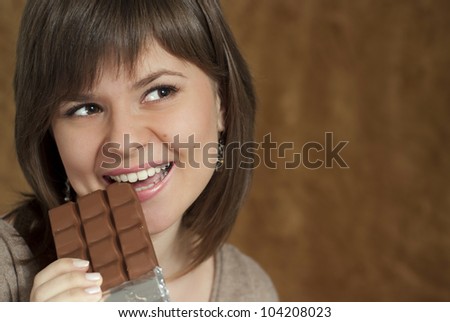 A beautiful Caucasian woman eats chocolate brown background