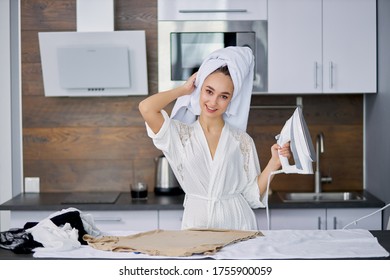 Beautiful Caucasian Woman Enjoy Ironing Clothes At Home, She Is Preparing To Go Outside, Stand Using Modern Iron, Wearing Bathrobe And Towel After Bath