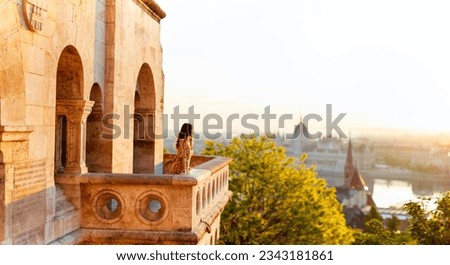 Beautiful caucasian woman enjoying morning view over Parliament in Budapest from Fisherman Bastion balcony