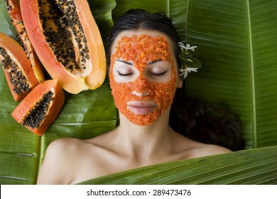 Beautiful caucasian woman having fresh papaya natural facial mask apply, skin care and wellness (outdoors). Facial vitamin mask of papaya slices at spa salon