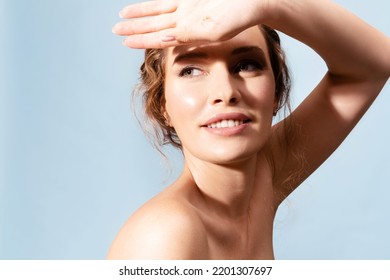 Beautiful  caucasian woman with healthy perfect face skin covering face with palm from sun. Smiling female with naked shoulders enjoying sunbathing. Advertising of sunscreen skincare cosmetics.