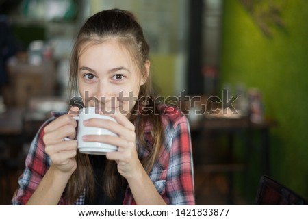 beautiful caucasian woman holding a cup of coffee in her hand at coffee shop