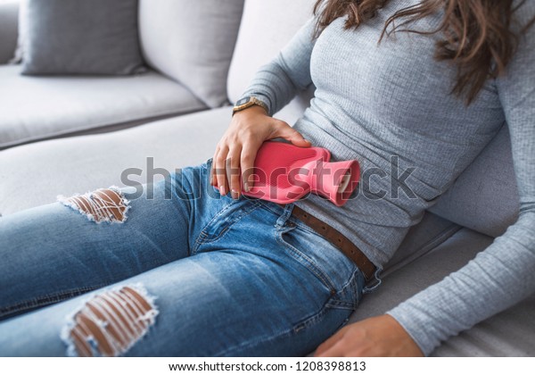 Beautiful caucasian woman\
lying in bed with hot water bag. Close up of woman belly with hot\
water bottle in bed. Beautiful young woman in bed, with hot water\
bag on her tummy