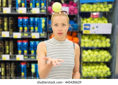 Beautiful Caucasian Woman Shopping Sports Equipment In Sportswear Store. Lady Throwing Tennis Ball In The Air.